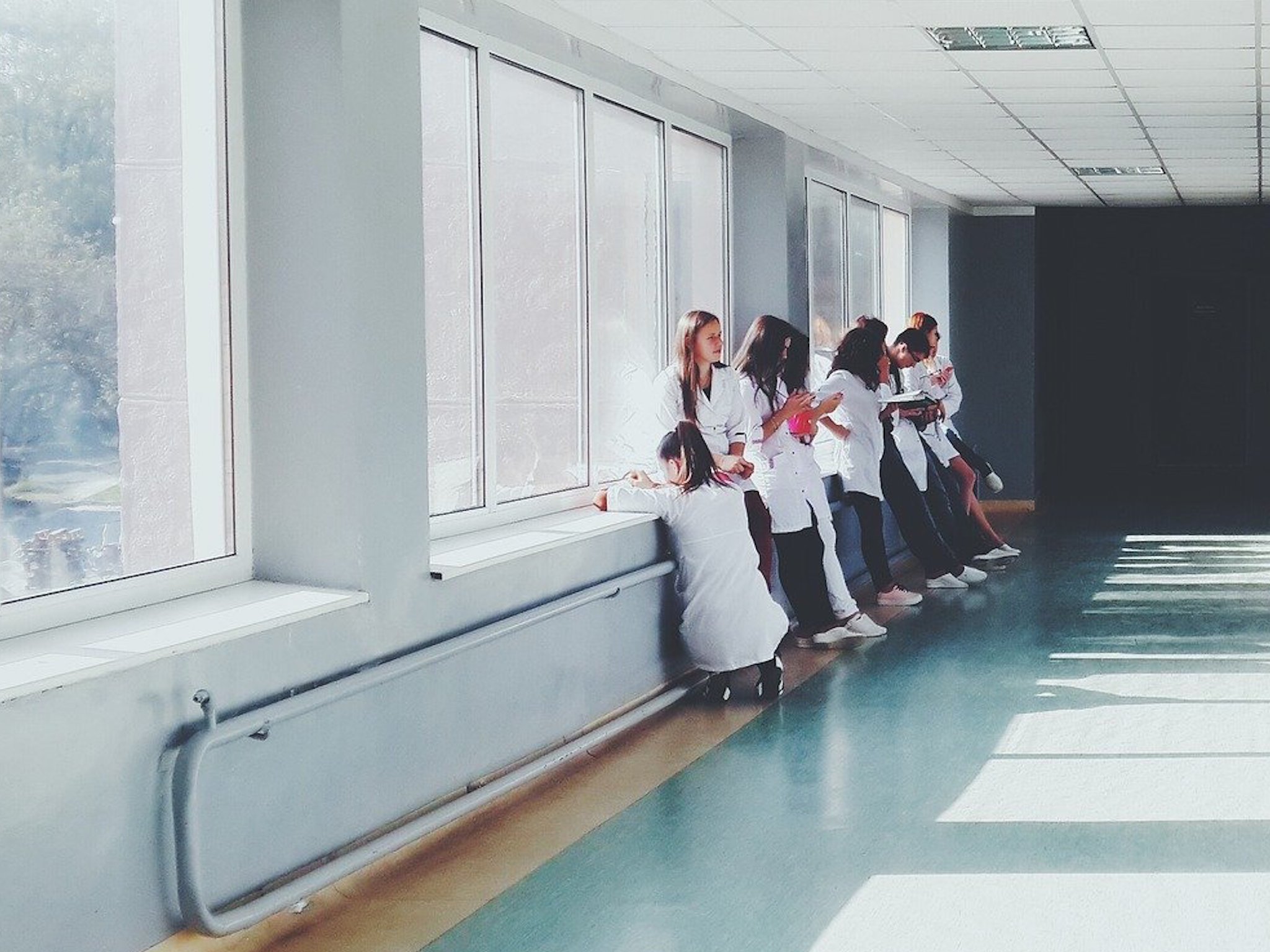 Studierende in weißen Arztkitteln warten auf ihren Einsatz im Krankenhaus.