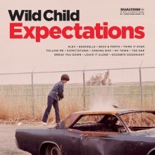 Albumcover von WILD CHILD - Expectations; Fot von einem Kind vor einem Hochsicherheits-Zaun, der ein Feld begrenzt, im Vordergrund ein verrostetes Auto