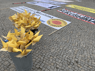 Atomkraft Nein Danke-Banner auf dem Boden, Eimer mit gelben Papier-Windrädern