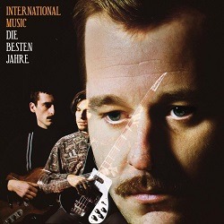 Cover von INTERNATIONAL MUSIC - Cool Bleiben; zwei weiße Männer mit Gitarren im Hintergrund, im Vordergrund das Gesicht eines weißen Mannes