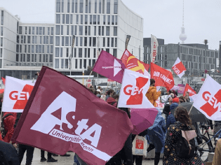 Studentisches Demonstranten mit Fahnen und Bannern vor dem Hauptbahnhof Berlin.