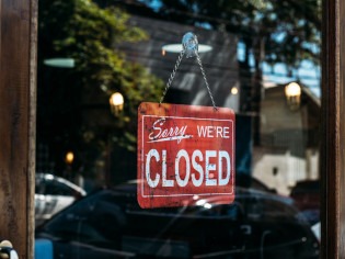 Schild mit der Aufschrift "Sorry we're closed" hängt im Fenster