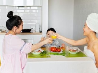 Foto von zwei asiatisch-stämmigen Frauen, die mit einem Kind am Frühstückstisch sitzen