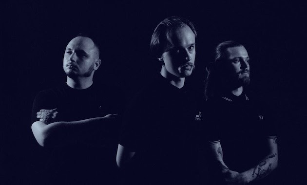 Drei Männer und Mitglieder der Belarusischen Band Molchat Doma vor einem dunklen Hintergrund auf einem Schwarz-Weiß Bild.
